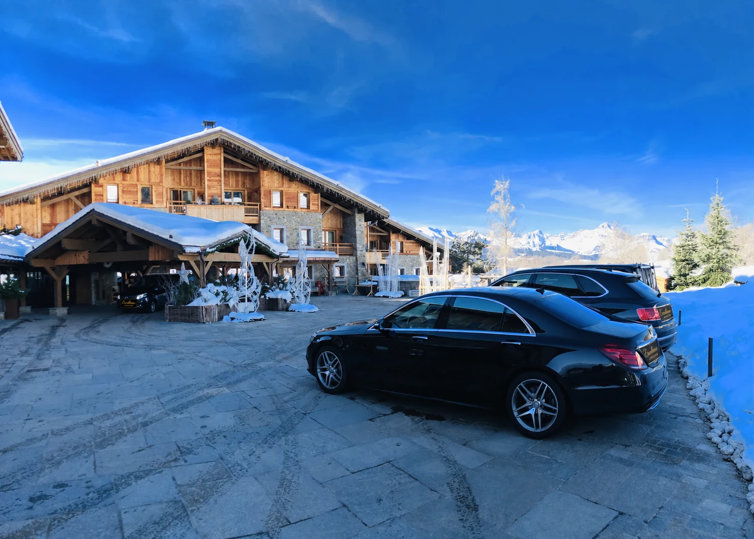 Archives d’hiver — ancienne génération de Mercedes Classe S devant un hôtel alpin.