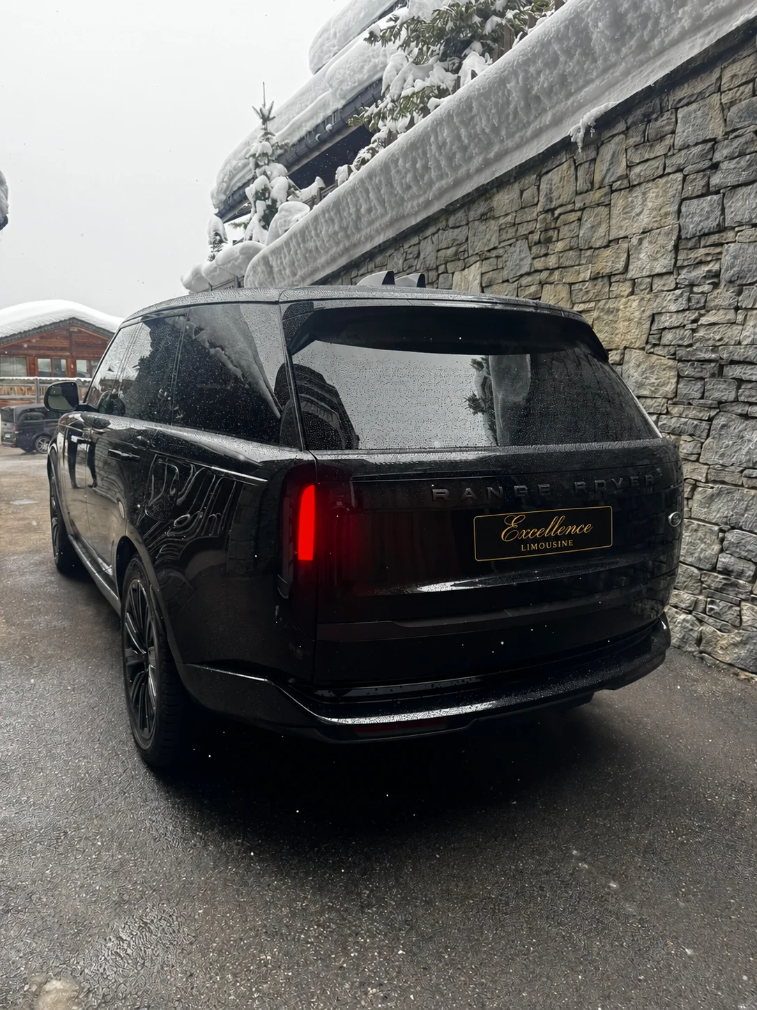 Range Rover vu de l’arrière près d’un chalet enneigé.