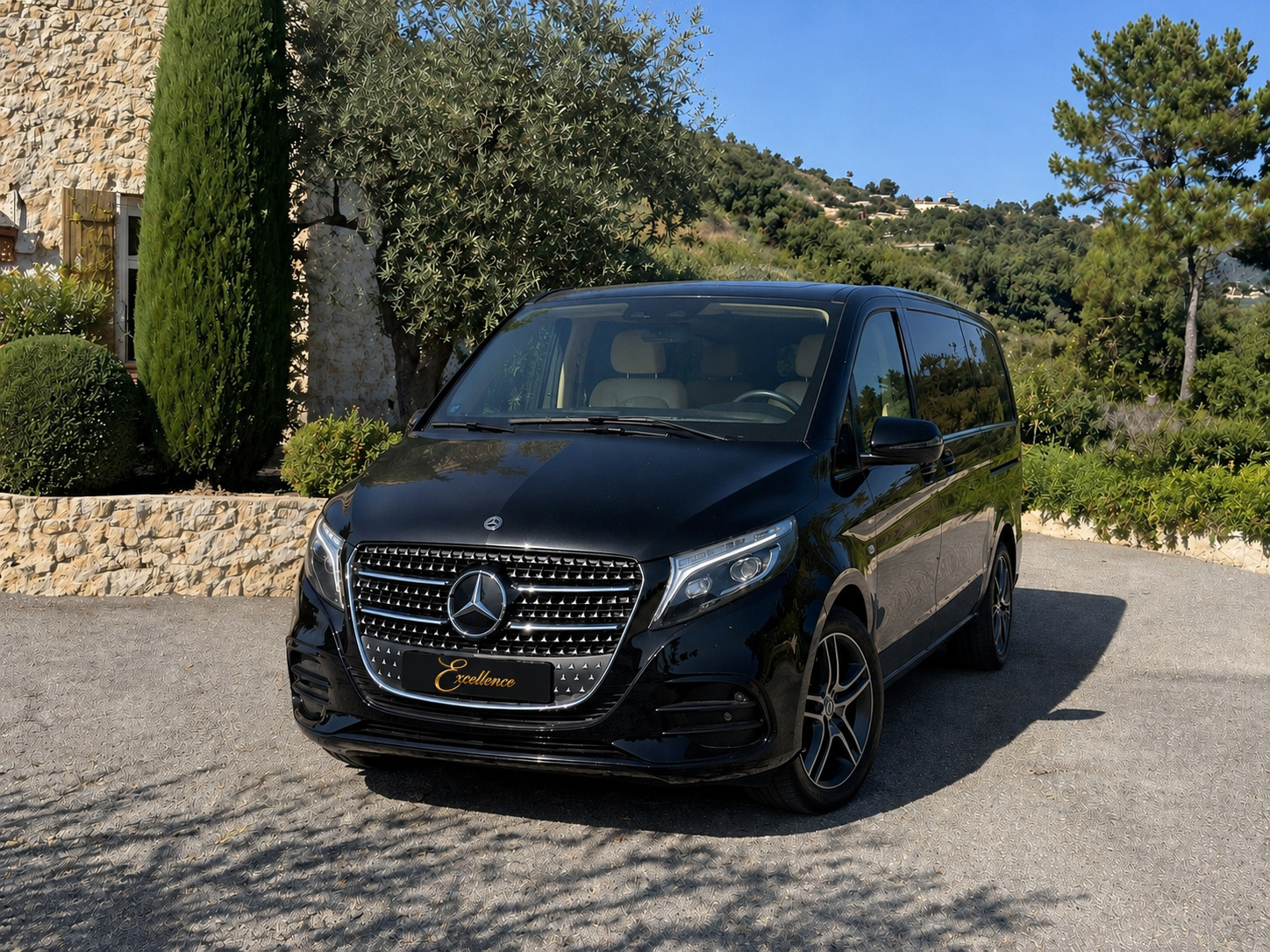 Schwarze Mercedes V-Klasse neben einer Steinmauer