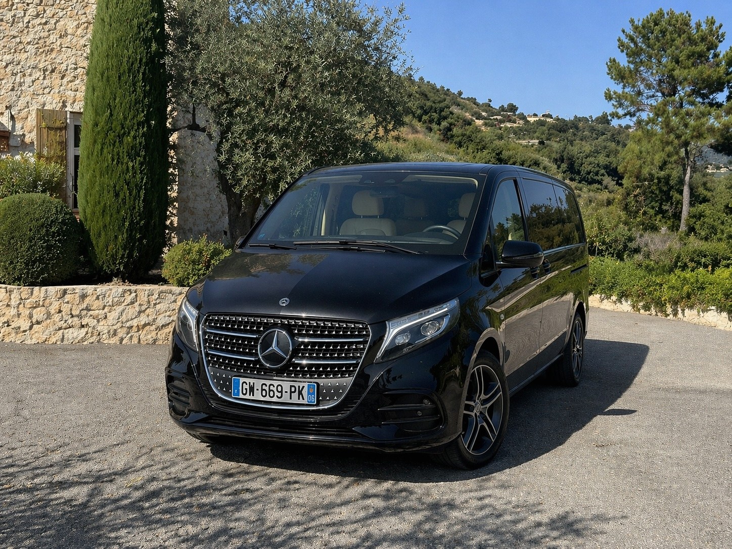 Black Mercedes V-Class parked beside a stone wall
