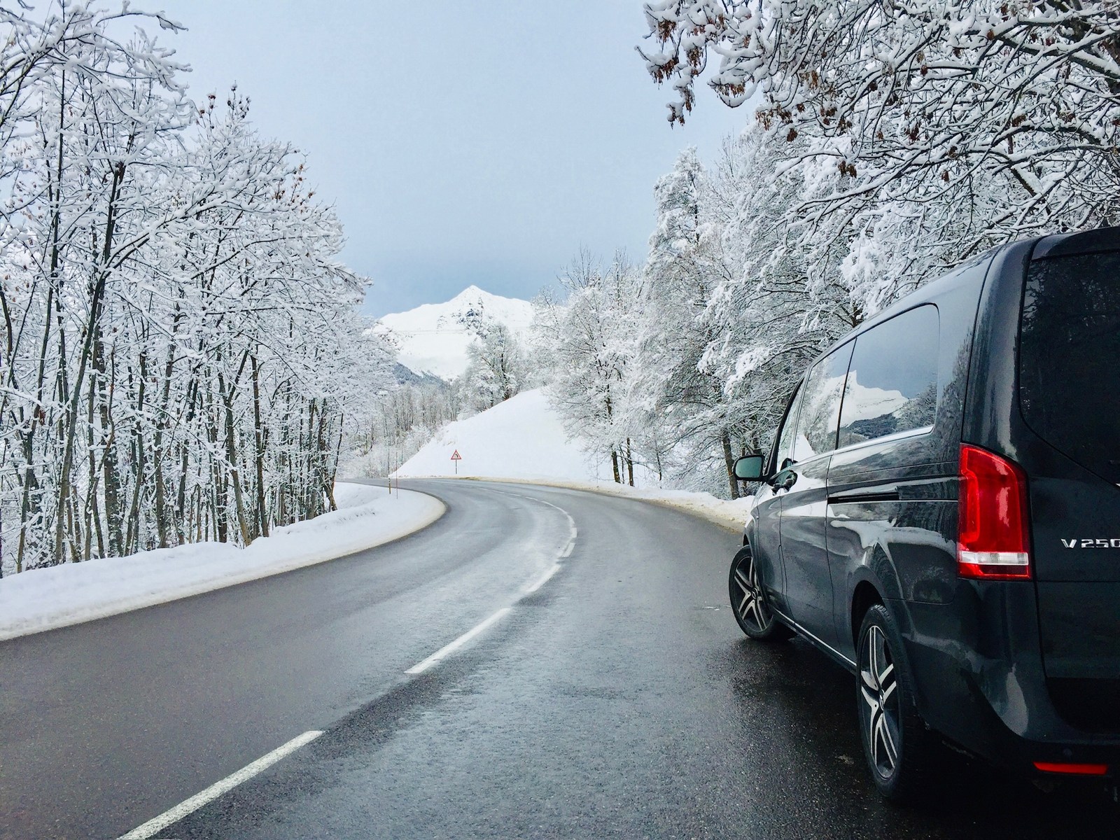 Mercedes Classe V au bord d’une route entourée d’arbres enneigés.