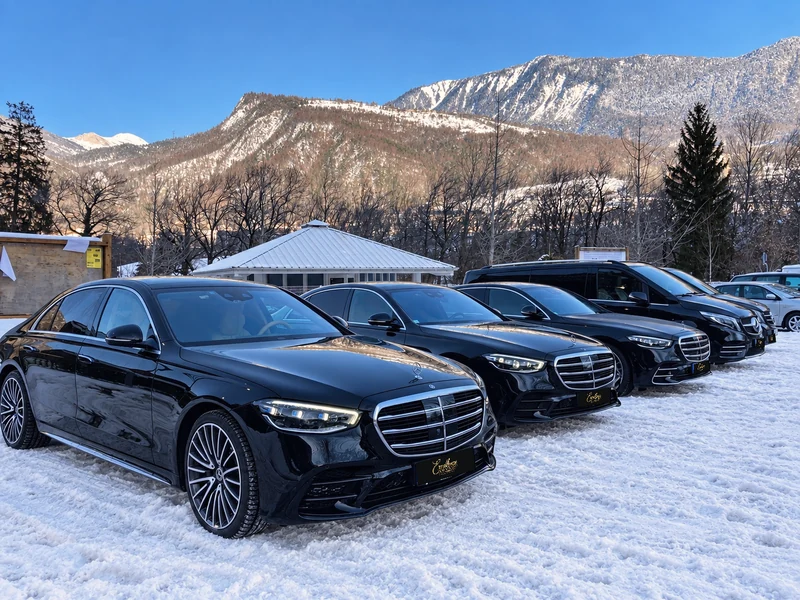Trois Mercedes Classe S noires et des vans alignés devant des montagnes enneigées, photographie d’archive de 2022.